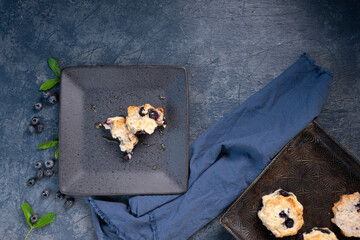 Freshly baked blueberry biscuits, scones, blue napkin and background, antique baking pan.  Berries and leaves.