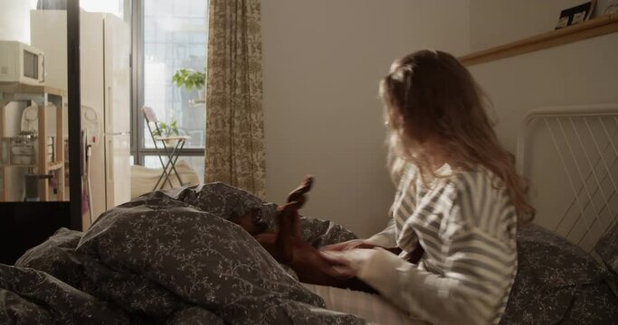 Woman on bed playing with pet dog
