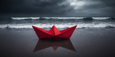 Red paper boat on the beach with stormy sea background.
