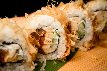Front view of sushi stuffed with cream cheese, seafood and cucumbers on a stand