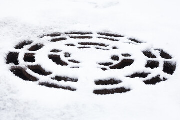 Round manhole covered with snow