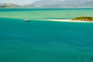 A boat nearby the sandy beach over a greenish emerald colored ocean
