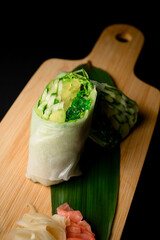 Top view of vegetables rolls on a wooden board with a green leaf, ginger and wasabi