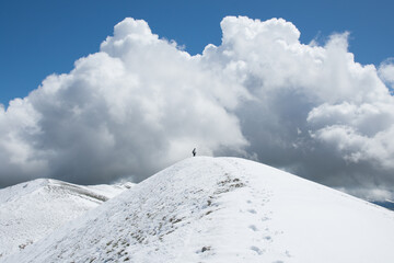 View of the summit of Monte Calvo against a big cloud and blue sky in Abruzzo, Italy