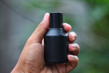 Bottle perfume male hand isolated on blurred background. young man holding bottle of perfume. man...