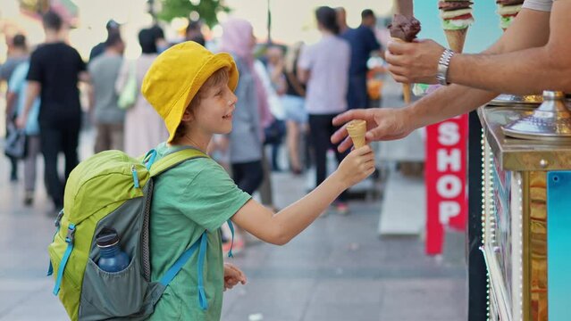 A playful moment unfolds as a boy anticipates the taste of creamy Turkish ice cream, only to be met with the mischievous antics of a skilled vendor. Amid the vibrant market bustle, the vendor's