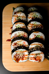 Black nori sheets wrapped on sushi decorated with sesame seeds and sauce