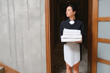 Female chambermaid holding clean white folded towels