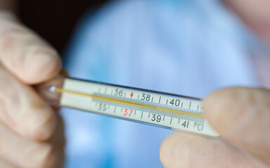 Hands holding medical thermometer.
