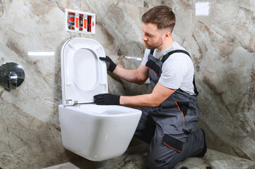 Professional plumber working with toilet bowl in bathroom