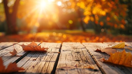 Beautiful empty wooden table with fall leaves, glowing sun set and blurry seasonal colors - obrazy, fototapety, plakaty