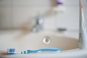 Blue toothbrush lying on a sink in the bathroom. Blurred background with copy space and bokeh.