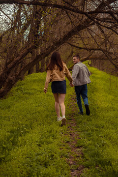 A rear view of a young man and woman running in the park, capturing a photo session in the nature reserve Valentine's Day
