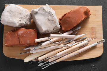 Clay and set of modeling tools on black table, top view