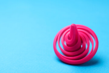 One pink spinning top on light blue background, closeup,. Space for text