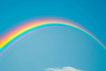 A vibrant rainbow stretching across the clear blue sky, adding a touch of magic to a summer day isolated on solid white background.