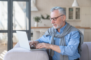 Confident mature old senior caucasian man businessman grandfather working on laptop, e-learning, university professor on lockdown. Home office, active seniors, freelance remote work