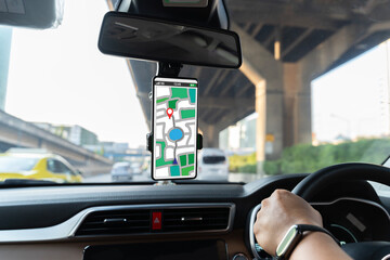 A person is driving a car with a phone mounted on the dashboard. The phone is displaying a map of...