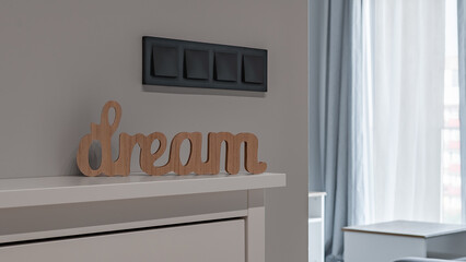 napis dream z drewna, stojący na półce, włączniki światła, mieszkanie