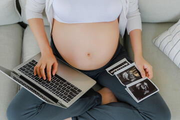 Close up crop Asian pregnant woman is and holding ultrasound 4d scan image touching her belly....