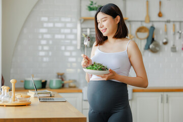 pregnancy, healthy food and people concept - close up of happy pregnant woman eating vegetable...
