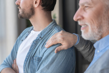 Close up shot of a caucasian old elderly senior man supporting his young adult son looking at the...