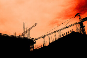 Residential building development and construction, back lit cranes and scaffold
