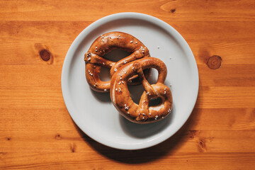 Top view of two freshly baked pretzels on a plate - 791785946