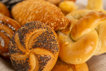 wicker basket overflowing with freshly baked pastries: cheese and poppy seed buns, pretzels, and...