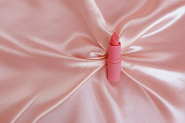 matte lipstick on a delicate pink background, pink silk fabric, close-up, the concept of decorative...
