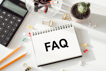 A notepad displaying the word FAQ sits next to a calculator, suggesting assistance with frequently asked questions or financial queries.