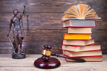 Law concept - Open law book, Judge's gavel, scales, Themis statue on table in a courtroom or law enforcement office.