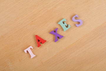 TAXES word on wooden background composed from colorful abc alphabet block wooden letters, copy space for ad text. Learning english concept.