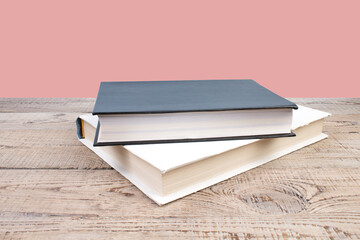 open book. Composition with hardback books, fanned pages on wooden deck table and pink background. Books stacking. Back to school. Copy Space. Education background.