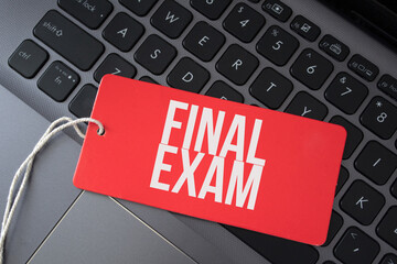 final exam word written on red paper note on computer keyboard.