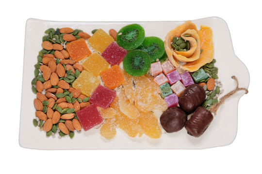 Variety of sweet desserts in plate for the holiday. Marmalade, candied fruit, mango, kiwi, nuts, seeds, chocolate candies and Turkish delight in a plate.