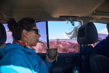 Argentine woman traveling in the back of a car, enjoying drinking mate, a hot drink that is a must...