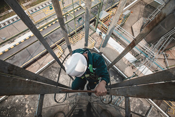 Top view male worker climbs up the ladder inspection stainless tank work at height