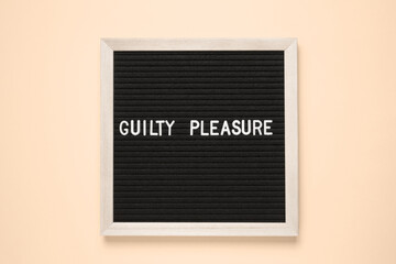 A rectangular black wooden board with Guilty Pleasure, featuring a stylish logo and graphics...