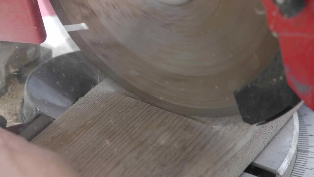 a carpenter accurately cuts wood on a table saw, amidst nature. Close up