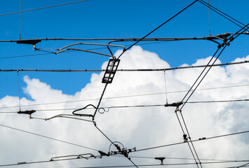 Electric wiring of city tram and bus traffic - in the background a mighty cloud in the blue sky