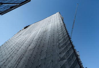 Renovation of a high-rise building. a tower crane. the building is covered with fabric during...