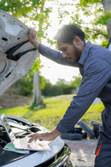 Young man checks broken car on the side of the road, long distance driving concept. Portrait of an Asian auto mechanic, auto repair, car service. and maintenance concept