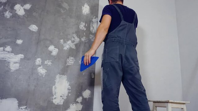 A man glues wallpaper on the floor in a room, Time lapse