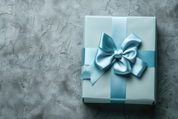 Light blue gift box with ribbon bow, top view, on gray concrete rough background with copy space. Present for Men's Day, Father's Day, Boss Birthday.