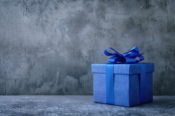 Blue present box stands on gray shabby surface and gray concrete rough wall on background with copy space. Present for Men's Day, Father's Day, Boss Birthday.