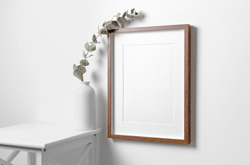 Portrait frame mockup for artwork, picture or print design on white wall with dry eucalyptus decor in vase