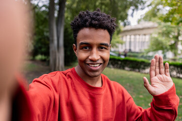 Friendly Young Man Waving Hi in a Park Setting
