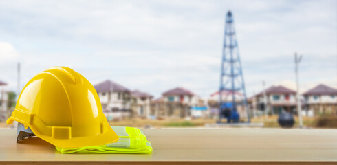 Yellow safety construction helmet on wood table with construction site background - 791830939