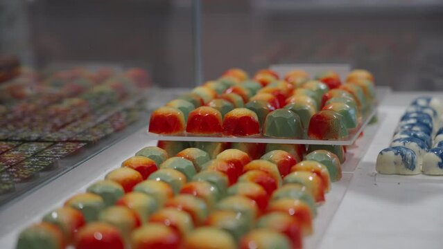 Rack focus on close up of colorful fancy chocolates on display in a specially candy shop